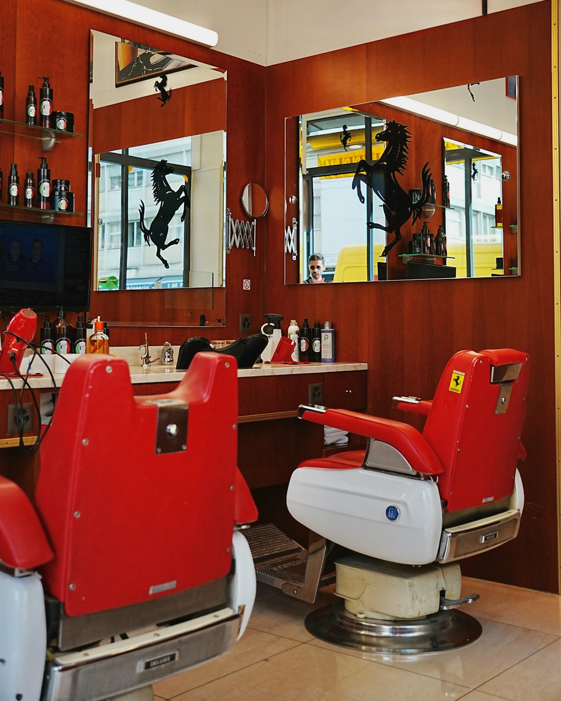 Poltrone da barbiere con loghi Ferrari in un salone alla moda.