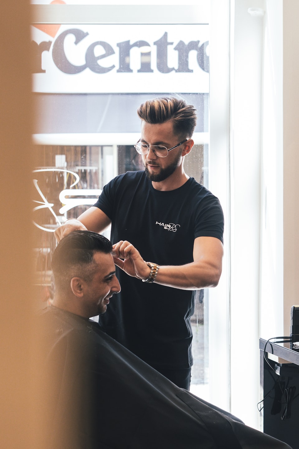 Barbiere che sistema i capelli di un cliente in un moderno salone da barbiere.