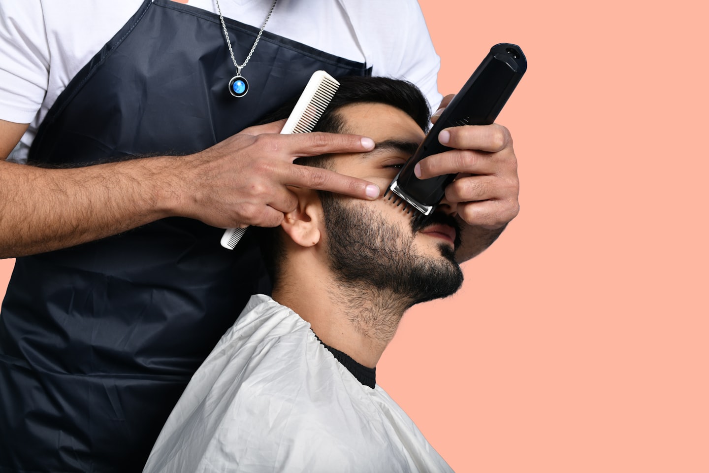 Un barbiere usa un tagliacapelli elettrico per curare la barba di un cliente.