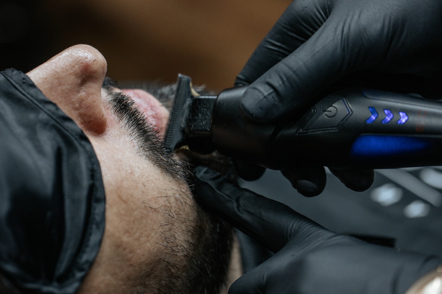 Un barbiere usa un tagliacapelli elettrico per accorciare la barba di un cliente.